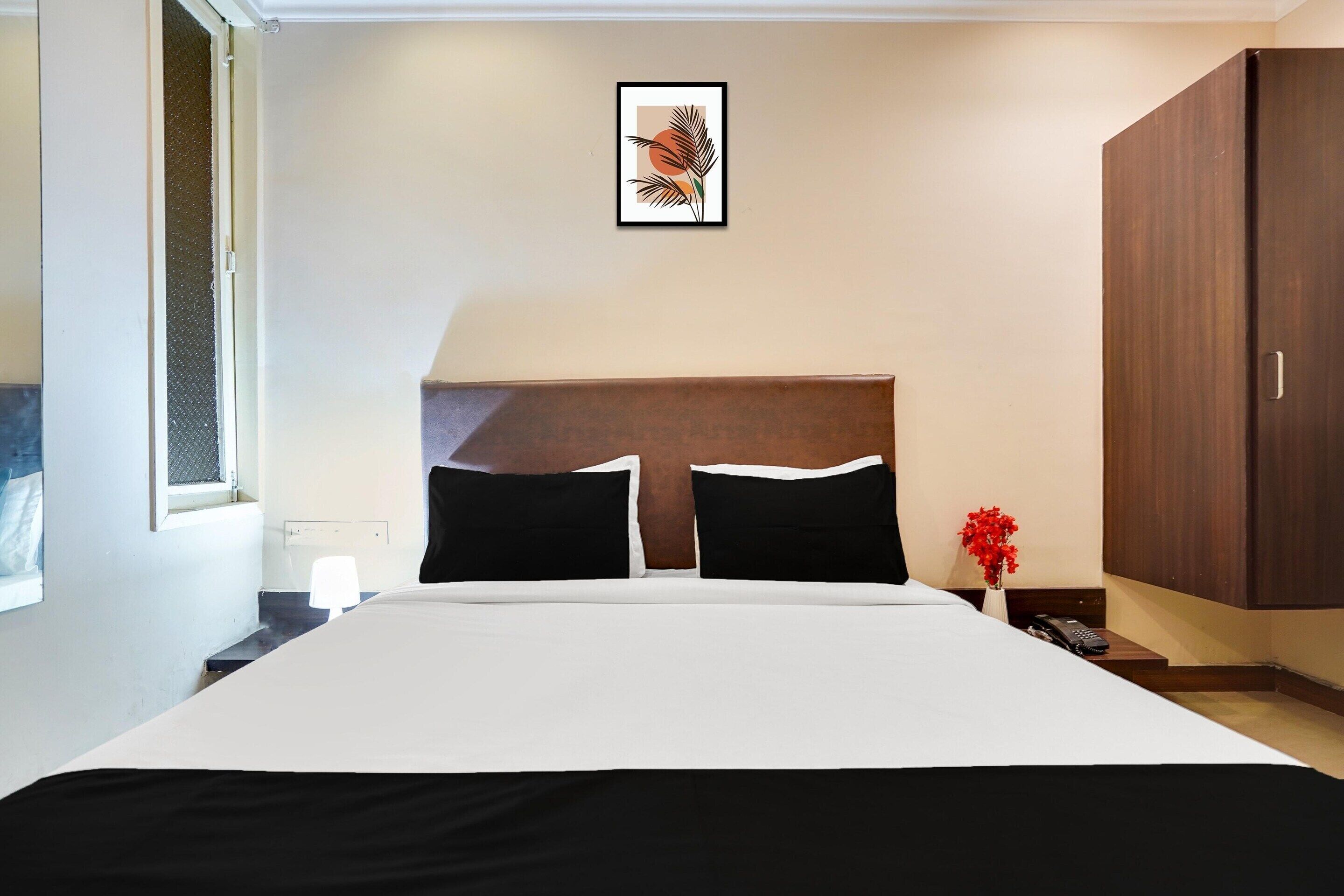 Une chambre d’hôtel avec un grand lit, une table de chevet, un tableau encadré au mur et une armoire.