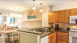 A modern kitchen with granite countertops, wooden cabinets, a built-in dishwasher, and a microwave. - Wyndham ON THE BEACH 3-BR condo in beautiful North Myrtle Beach, LAZY RIVER! (North Myrtle Beach)