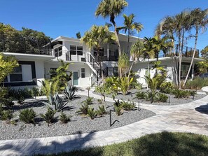 Un immeuble moderne à plusieurs étages, doté d’une cour aménagée avec des palmiers et diverses plantes.