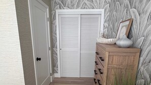 Ein Flur mit einem Holzkasten, einer weißen Tür und einem Wandpapier mit Muster.