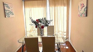 A dining area with a glass table, two chairs, a vase with flowers, and a window with curtains. - Fully equipped apartment for 6 - Relax and enjoy Viña del Mar (Viña del Mar)