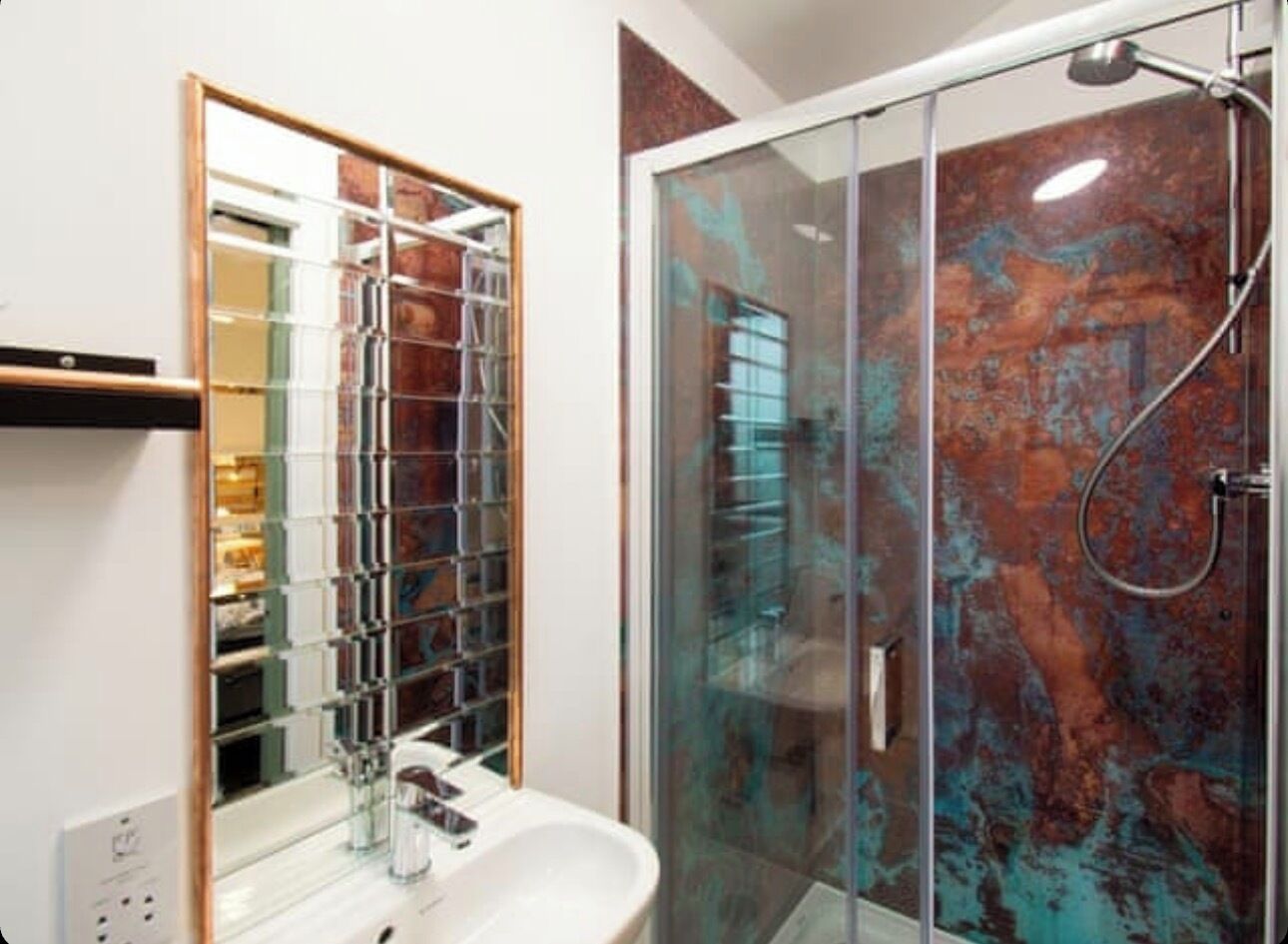 Une salle de bain moderne avec une douche à parois de verre, un lavabo blanc et un grand miroir avec un cadre en bois.