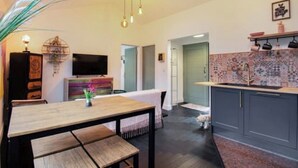 A modern kitchen with a dining area, a TV, and a pet visible. - Diesel's Desirable Den - Luxury rural 2 bed cottage, peaceful walks and stays UK (Maidstone)