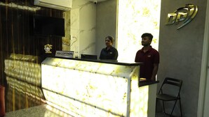 Un comptoir d’accueil avec un plateau en marbre, une enseigne indiquant « Réception » et un logo sur le mur.