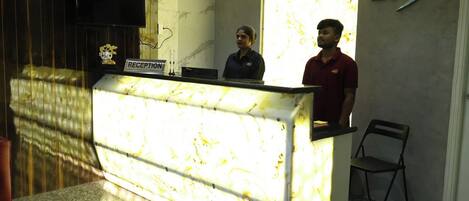 A reception desk with a marble top, a reception sign, and a logo on the wall.