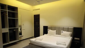 Une chambre d’hôtel avec un lit, une armoire, un miroir et une table de chevet.
