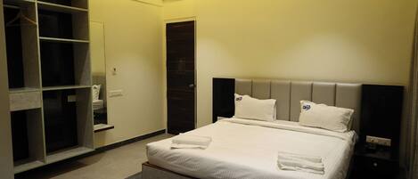 A hotel room with a bed, a wardrobe, a mirror, and a bedside table.