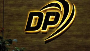 Un logo composé des lettres « DP » dans une police stylisée et lumineuse, sur un fond en bois.