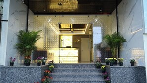 L’entrée d’un hôtel, avec une façade en marbre, un comptoir d’accueil et des marches menant à l’entrée.