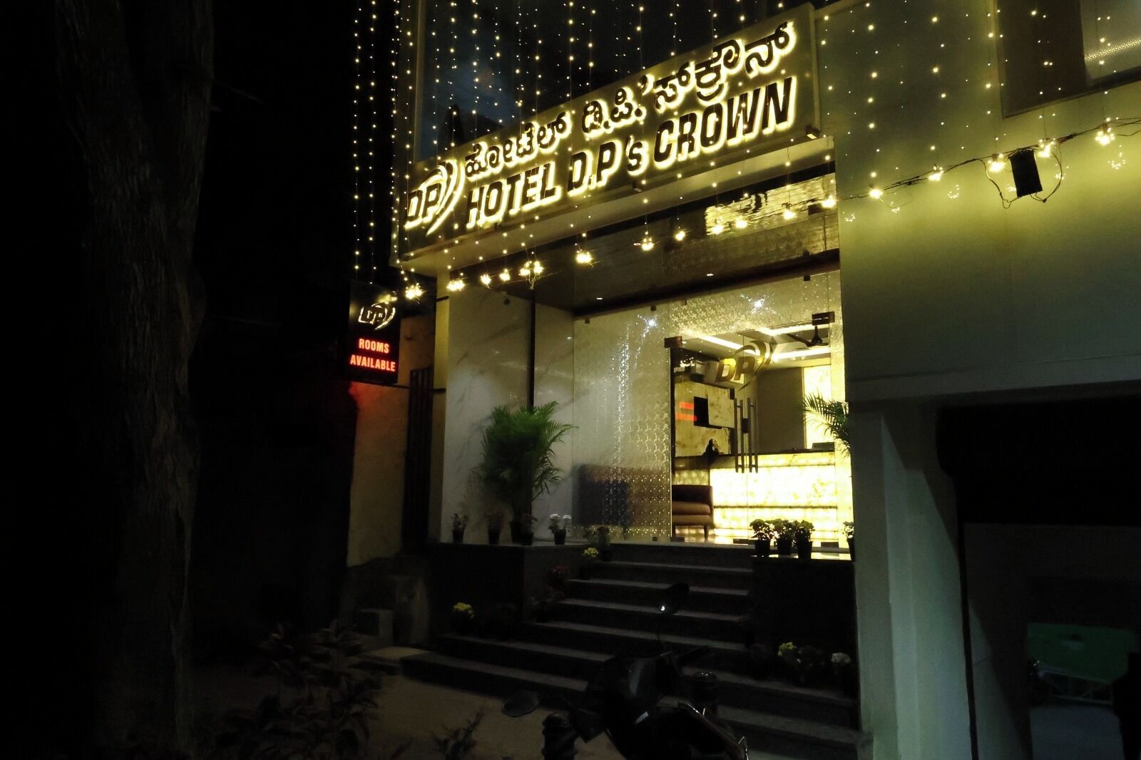 Entrada de hotel con un cartel que indica "HOTEL D.P'S CROWN" y "HABITACIONES DISPONIBLES".