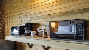 Una pared de madera con una estantería que muestra una cafetera, tazas, un recipiente y un cabecero de Samsung.