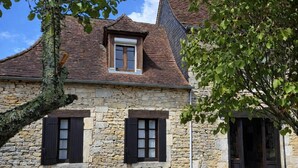 A stone building with a pitched roof, two windows with shutters, and a door. - Charming stone house in Périgord • Peaceful • Garden • 8 guests (Coulaures)