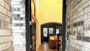 A doorway leading into a room with a wooden floor and a black doormat with "Oh, hello." - Wonderful 4-bedroom house with AC in tranquil Houston neighborhood (Houston)