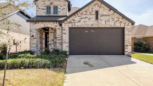 A two-story house with a garage, brick exterior, and a landscaped front yard. - Wonderful 4-bedroom house with AC in tranquil Houston neighborhood (Houston)