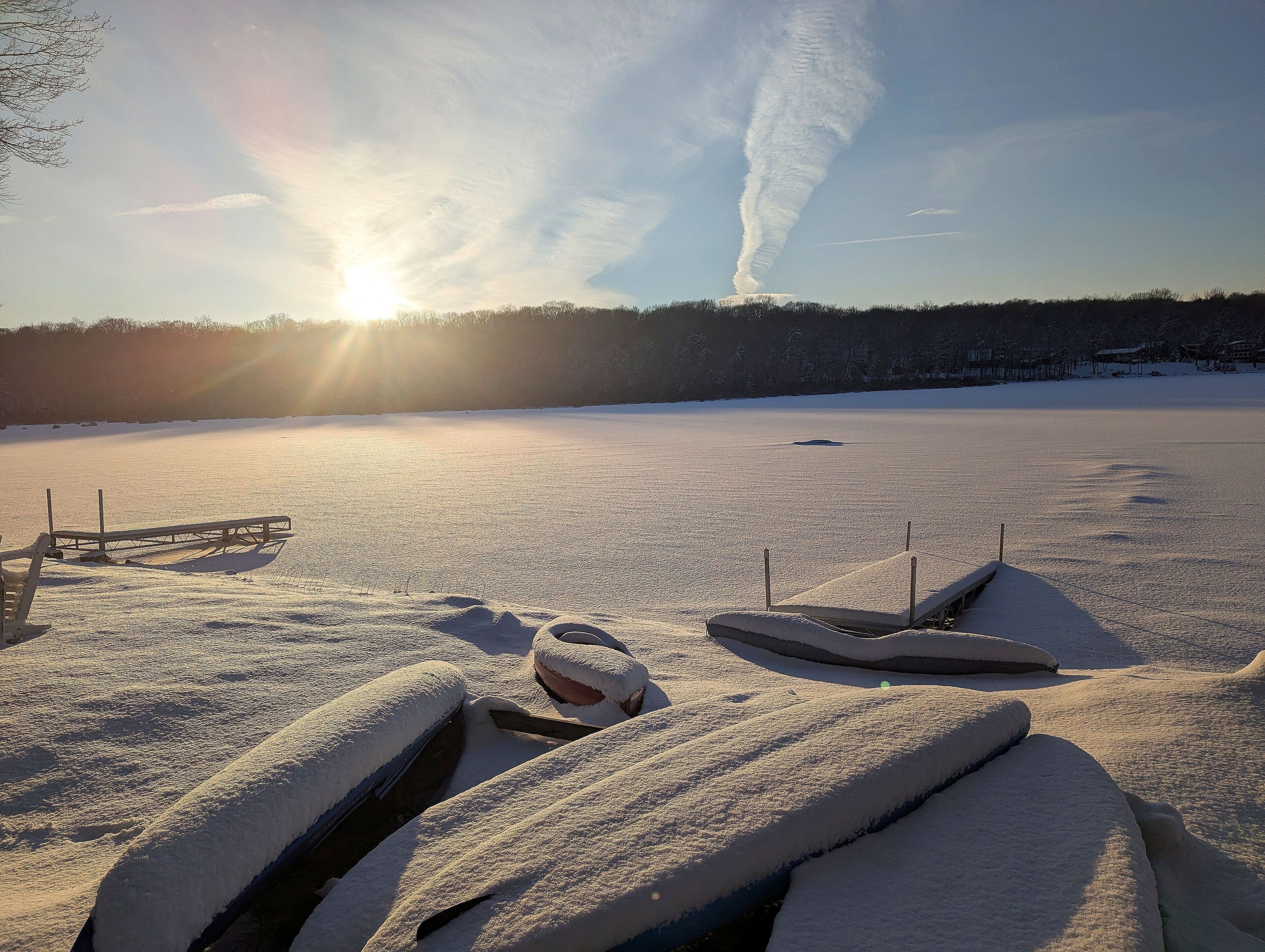 A snow-covered landscape with a clear sky and the sun setting or rising.