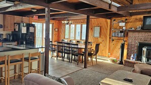 A cabin interior with a kitchen, dining area, and fireplace. - Two Adjacent Lakefront Homes w/Docks, Boats, Firepit – Sleeps 24 (Pocono Lake)