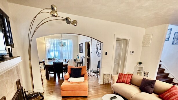 Un amplio salón con un sofá, un reposapiés y una mesa de comedor al fondo.