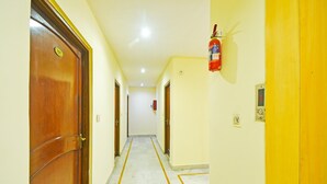 A hallway with wooden doors, a fire extinguisher, and a digital clock. - Classic Hotel Rishi (Jaipur)