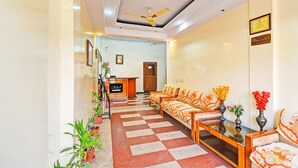 A hotel lobby with a reception desk, sofas, a checkered floor, and potted plants. - Classic Hotel Rishi (Jaipur)