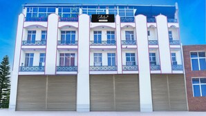 A multi-story building with a sign reading "Collection." It has balconies with metal railings, large garage doors, and a clear blue sky in the background. - Classic Hotel Rishi (Jaipur)