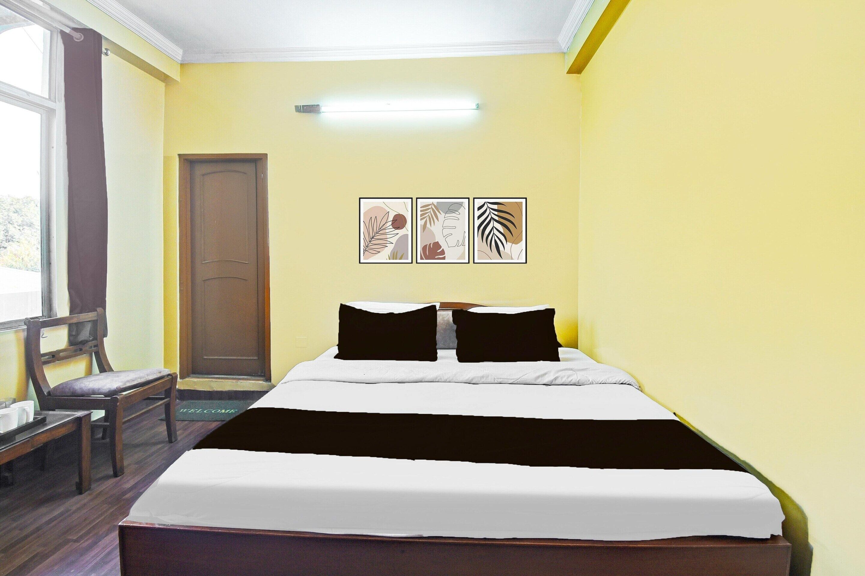 A hotel room with a bed, a chair, a desk, and a window.