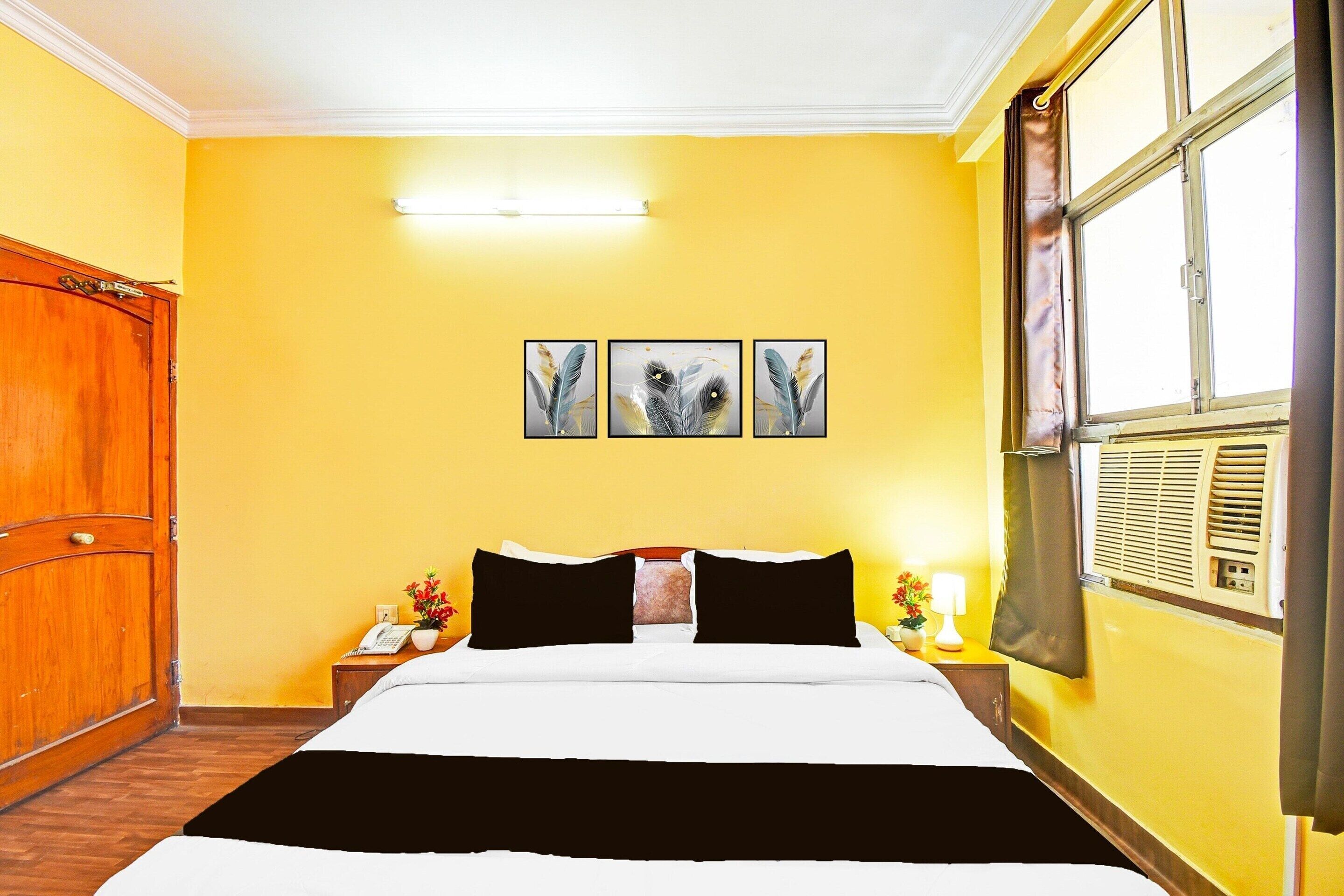A hotel room with a bed, a nightstand, a lamp, and a window with curtains.