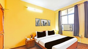 A hotel room with a wooden bed, a nightstand with a phone, and a window with curtains. - Classic Hotel Rishi (Jaipur)