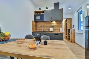 A modern kitchen with a wooden table, a coffee maker, and a microwave. - Apartments Seventy Seven - A1  (1 bedroom, 2+2), Mountain View, Pet Friendly (Kranjska Gora)