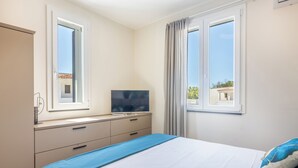 Un dormitori amb un llit, televisió, finestra i vistes a edificis.