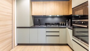 Una cuina moderna amb armaris de fusta clara, un rentamigles d'acer inoxidable i un forn encastrat.