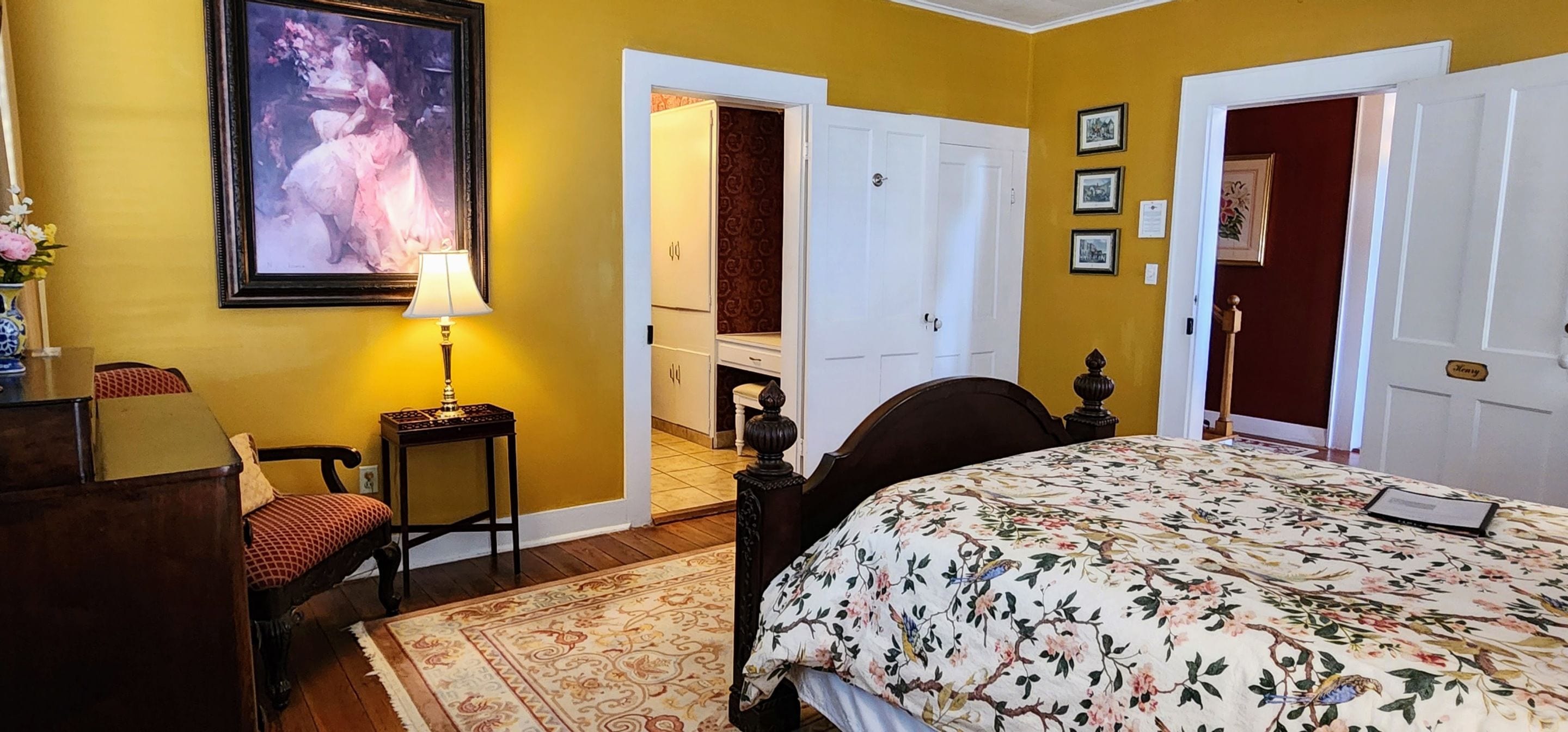 Un dormitorio con cama, una silla, una lámpara, un cuadro y una puerta.