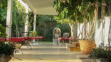 An outdoor patio area with a covered seating arrangement, a decorative stone structure, and potted plants.