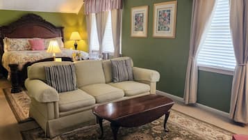 A room with a bed, a sofa, a coffee table, and two framed pictures on the wall.