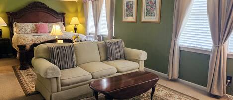 A room with a bed, a sofa, a coffee table, and two framed pictures on the wall.