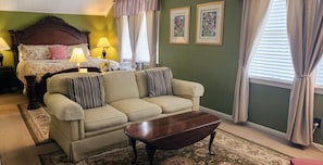 Quarto com cama, sofá, mesa de centro e duas imagens emolduradas na parede.