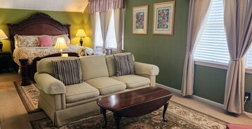 Una habitación con una cama, un sofá, una mesita de café y dos cuadros en la pared.
