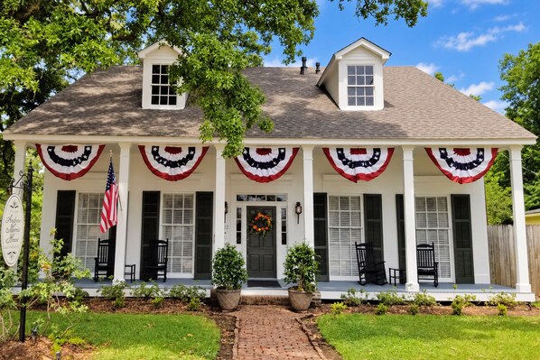 A two-story house with a porch decorated with American flags and a wreath. - Andrew Morris House Bed and Breakfast (Natchitoches)