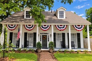 A two-story house with a porch decorated with American flags and a wreath.