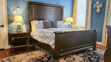 A bedroom with a dark wooden bed, two bedside tables with lamps, a floral-patterned bedspread, and a patterned rug.