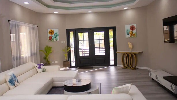 A living room with a sectional sofa, a coffee table, and a door leading outside.