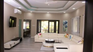 A modern living room with a sectional sofa, a coffee table, and a TV mounted on the wall.
