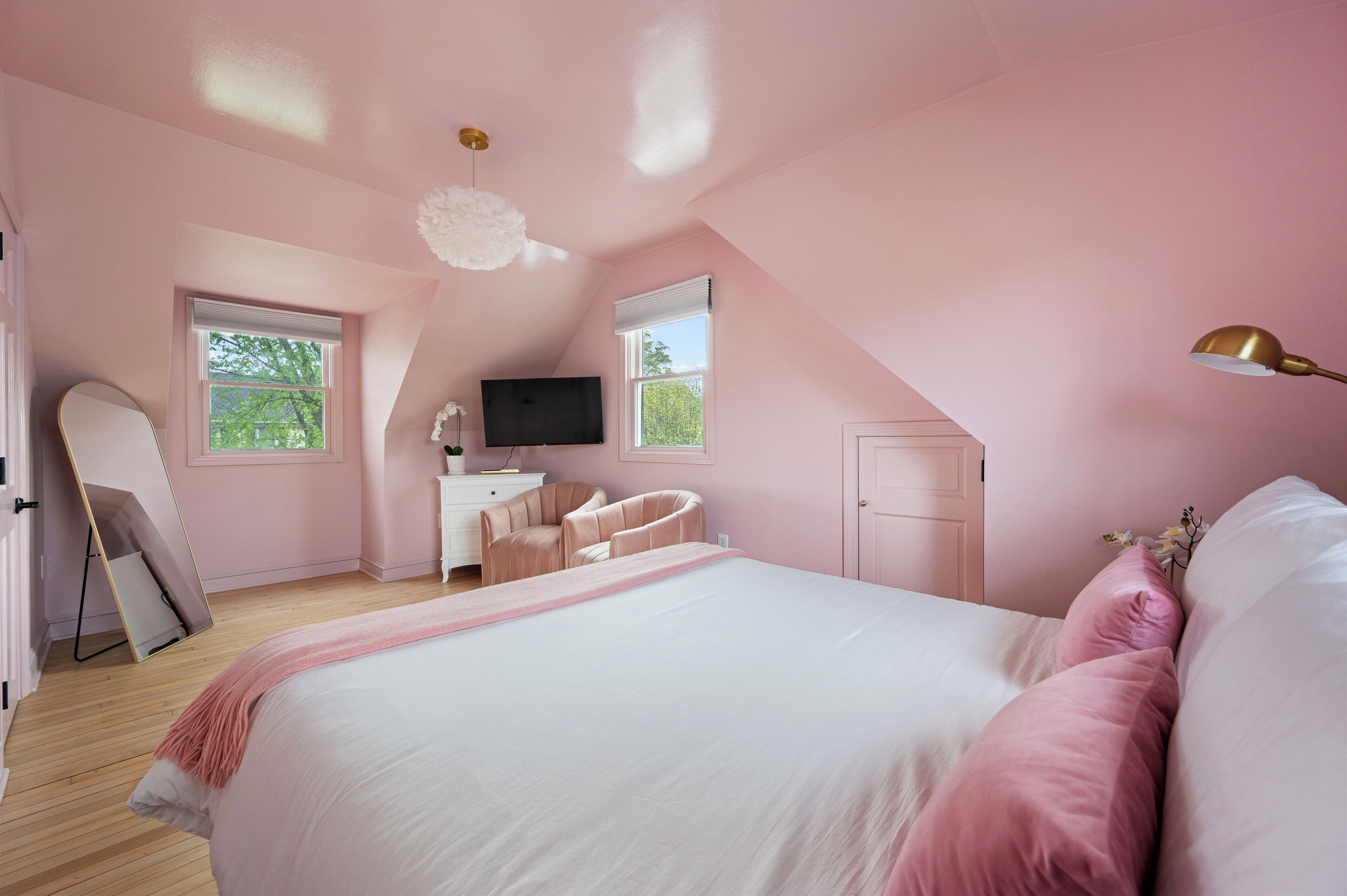 Un dormitorio con una cama grande, un escritorio, una silla, un televisor y una ventana.