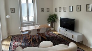 Un salon moderne comprenant un coin repas, un grand téléviseur et une plante en pot.