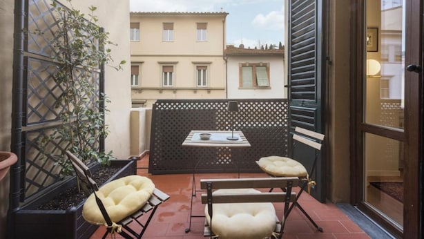 Un petit espace extérieur aménagé avec deux fauteuils confortables et une table, le tout délimité par une clôture en treillis.