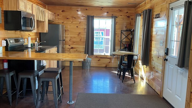 Interior de uma cabana de madeira com cozinha, banquetas e mesa de jantar.