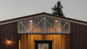 A modern building with a wooden facade, a black door with a curtain, and a small porch area.