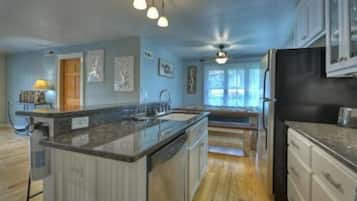 A spacious kitchen with a central island, wooden flooring, and pendant lighting.