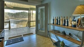 Una habitación con piso de madera, una puerta de vidrio que da al exterior y un estante con botellas.