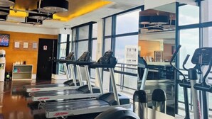A gym with treadmills, exercise bikes, and a coffee station. - STAYLUXIA Gramercy 2BR Junior Suite w/Balcony Free Pool Gym Netflix & Amenities  (Makati)