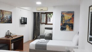 A hotel room with two beds, a desk, a chair, a TV, and paintings on the walls. - Hotel Efesian B&B City Center - Harbour (Kuşadası)